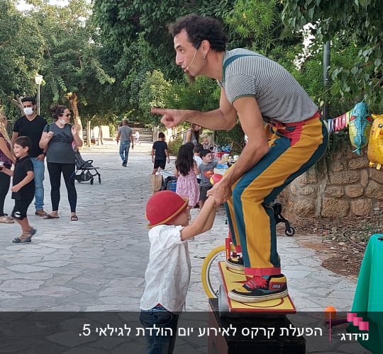 איש על חד אופן מדבר עם ילד בכובע אדום